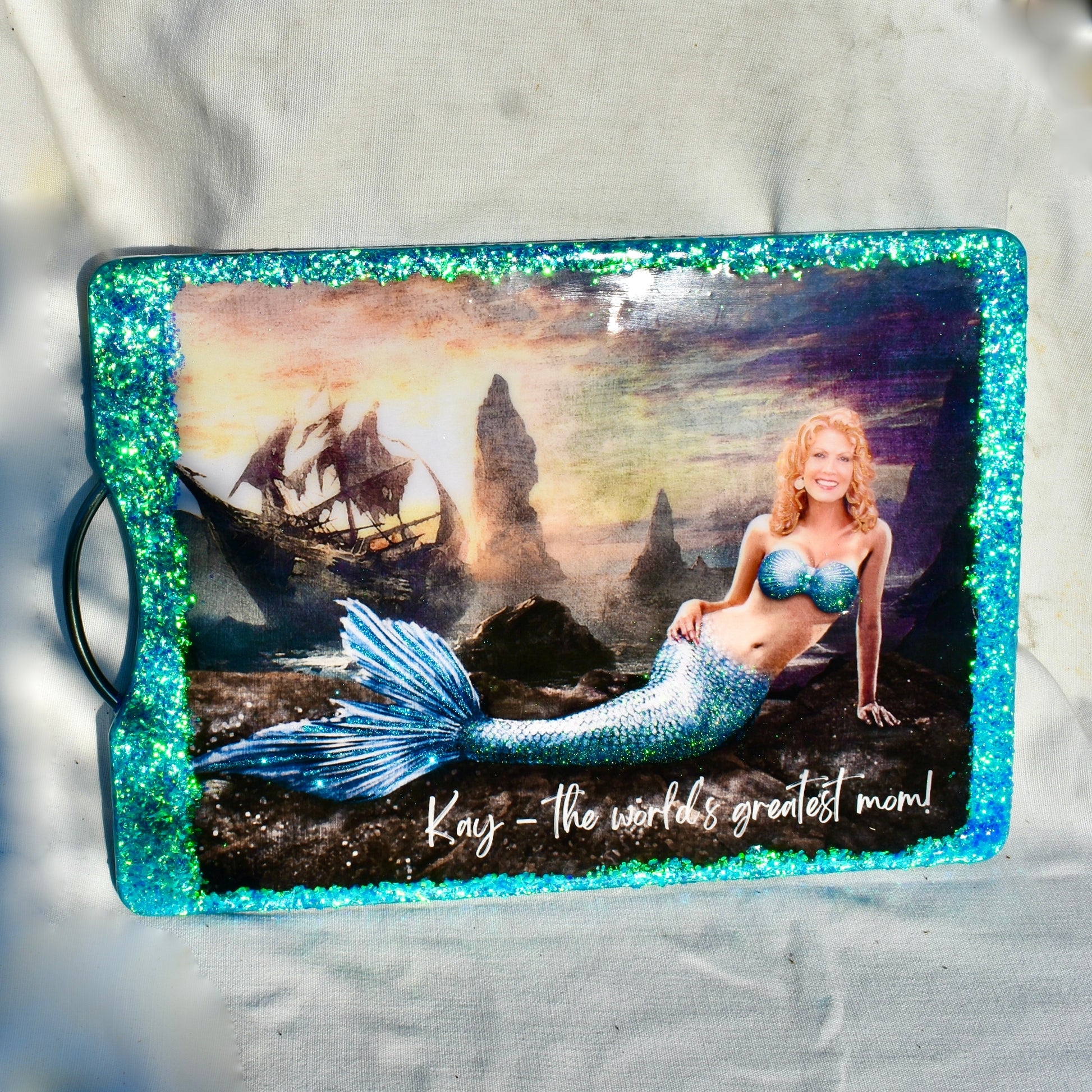 This custom charcuterie board features a  mermaid with a photo of the gift recipient.  The edges are embellished with holographic glitter.